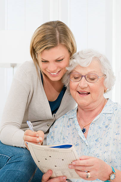 Active senior lady solving crosswords puzzle with the help of her young granddaughter.